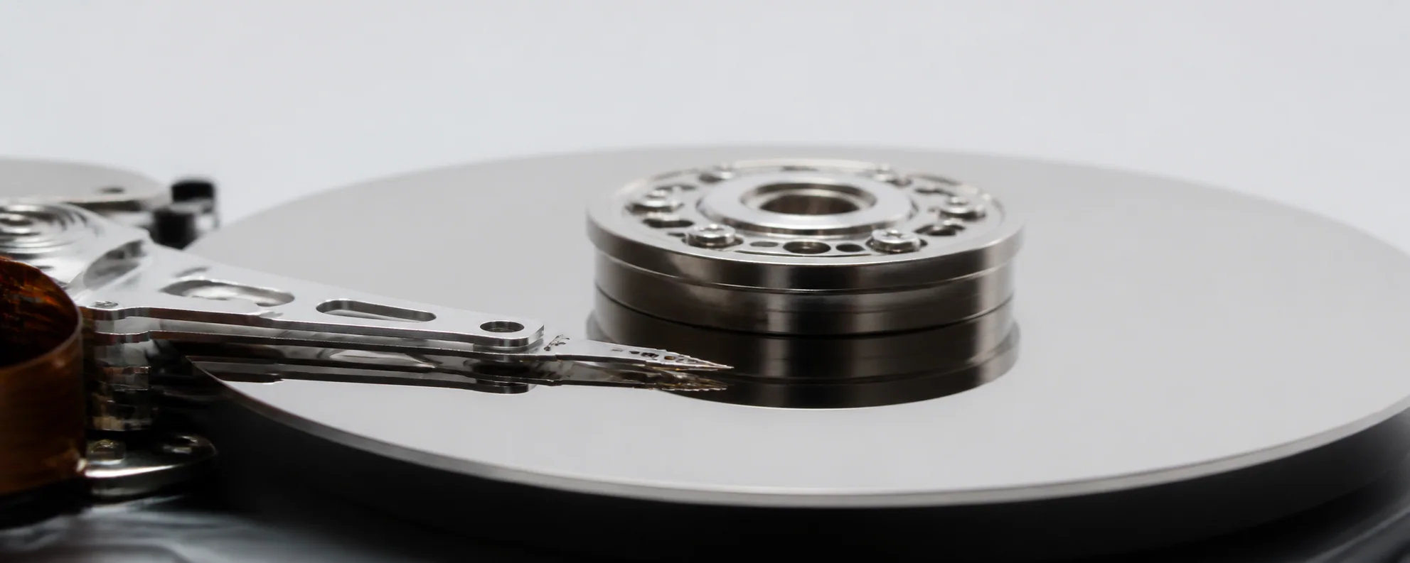 Macro dell'interno di un hard disk: il piatto specchiato e la testina di lettura